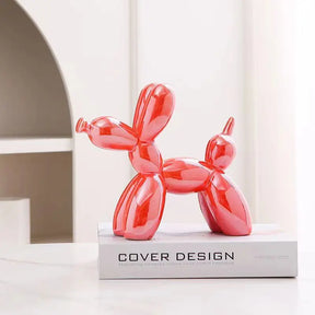 A Escultura Decorativa Mini Dog Balão é uma representação adorável de um cachorro segurando um balão, irradiando charme e alegria em sua forma compacta.  Da lojaorgnaizeja.com